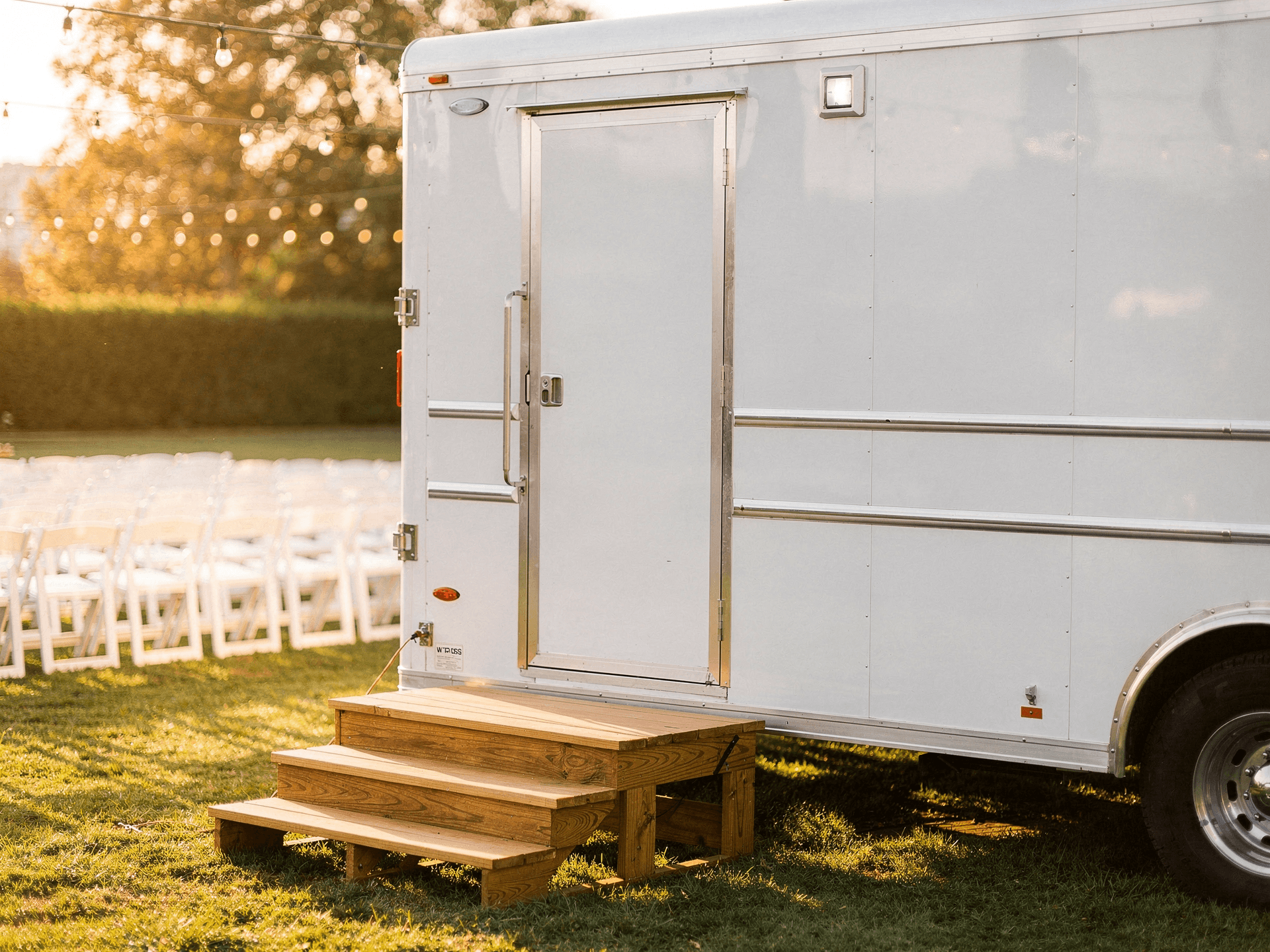 White luxury restroom trailer at an outdoor wedding venue